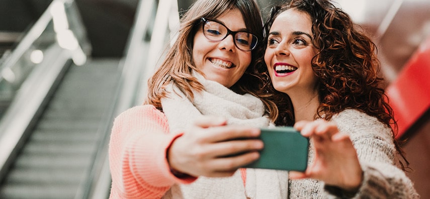 Deux femmes regardant un smartphone en riant.